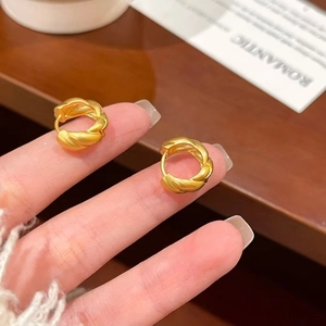 Close-up of matte gold twisted rope hoop earrings with detailed metal texture and clasp