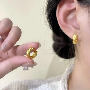 Elegant gold twisted hoop earrings with a matte finish and french croissant texture design
