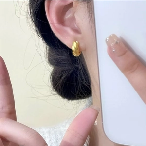 Golden twisted croissant hoop earrings with matte finish shown on model ear