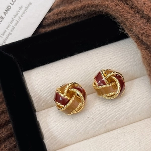 Twisted knot earrings with red enamel and gold finish displayed in jewelry gift box