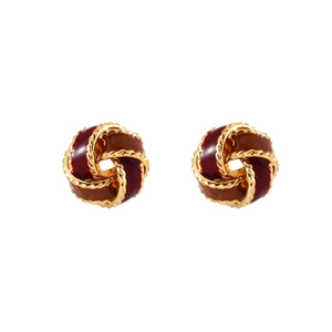Detailed view of twisted gold-rimmed earrings with deep red and coffee enamel inlay