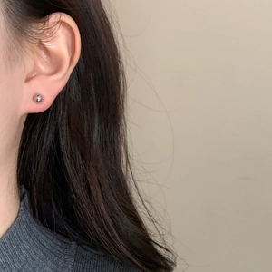Boucles d'oreilles boules argentées minimalistes avec finition polie sur une oreille