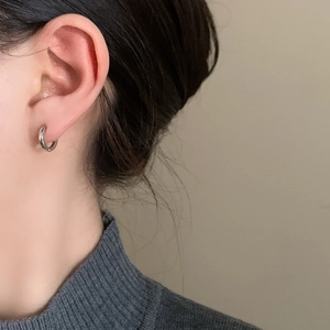 Boucle d'oreille anneau argenté minimaliste portée par un mannequin en col roulé