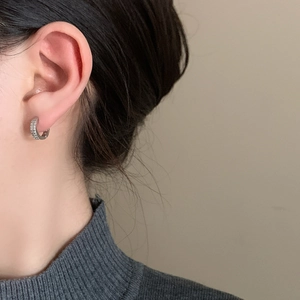 Gros plan détaillé d'une boucle d'oreille créole argentée sertie de zircons sur un mannequin