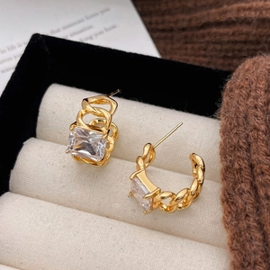 Goldene Kettenglied-Ohrringe mit eckigen Zirkonia-Steinen in einer beigen Samt-Schmuckbox