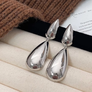 Polierte silberne Tropfenohrringe in Etagenform auf einer minimalistischen Textur