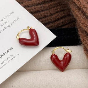 Orecchini a cuore rosso minimalisti placcati in oro su sfondo decorativo autunnale