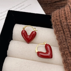 Eleganti orecchini a cuore in smalto rosso e finitura dorata su portagioie da esposizione