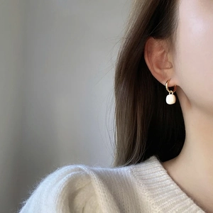 Elegant gold hoop earrings with cream geometric square pendants shown on model