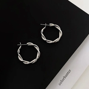 Detailed view of silver twisted rope hoop earrings with intricate metallic texture