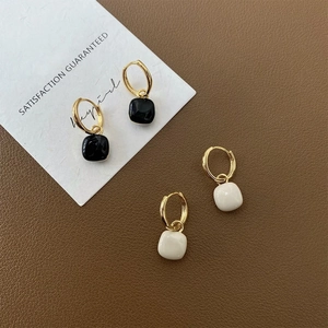 Detail shot of minimalist square pendant earrings in black and white on leather