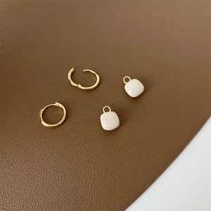 Macro detail of geometric square earrings with gold hoops on a leather background