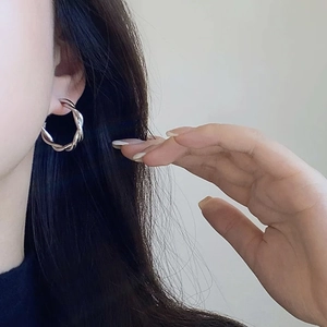 Detail of silver twisted rope hoop earring worn by a model in a minimalist style