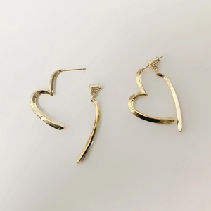 Minimalist gold-plated geometric heart and curved bar earrings on a white background
