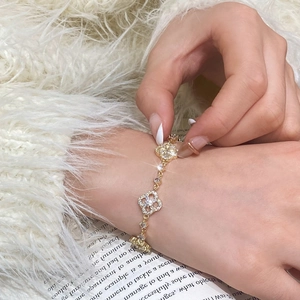 Macro detail of gold-plated clover bracelet with sparkling cubic zirconia on a wrist