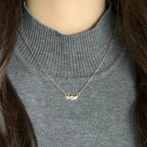 Minimalist 18K gold necklace with geometric zircon pendant worn on a grey turtleneck