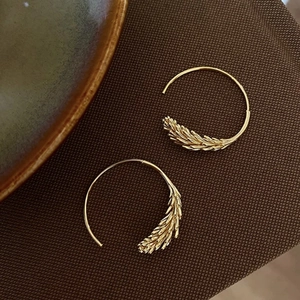 Boucles d'oreilles créoles dorées avec motif d'épi de blé sur tissu texturé de qualité
