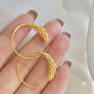 Vue détaillée des boucles d'oreilles anneaux épi de blé doré avec texture de grain précise
