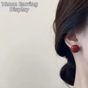 Detailed view of a 16mm deep red pearl stud earring worn on a model's ear