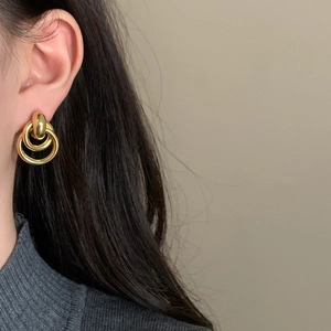 Minimalist double circle nested earrings in gold finish worn by a model in a grey sweater