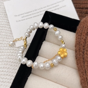 Natural freshwater pearl bracelet with a gold flower charm in a luxury jewelry box