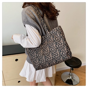 Detailed view of large leopard print tote bag worn by model in a minimalist setting