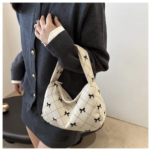 Detail of off-white corduroy hobo bag featuring black bow print and quilted texture