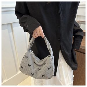 Detail of grey corduroy underarm bag with black bow patterns and quilted texture