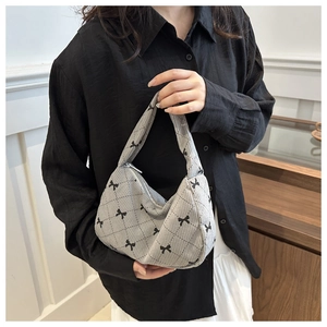 Detail of grey corduroy shoulder bag with black bow print and zipper closure
