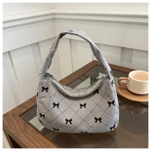 Detail of gray corduroy hobo bag with quilted diamond pattern and black bow embroidery