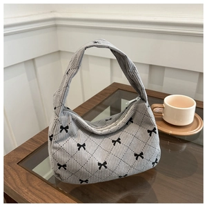 Detail of grey corduroy underarm bag featuring black bows and diamond quilted patterns