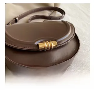Dettaglio macro della borsa a sella in pelle marrone vintage con fibbia in metallo oro