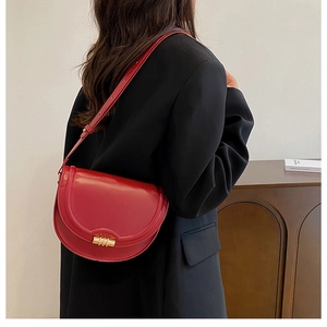 Modella indossa borsa a sella rossa con chiusura dorata su un blazer nero oversize