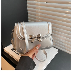 Macro detail of silver mini square bag featuring a metallic bow buckle and leather strap