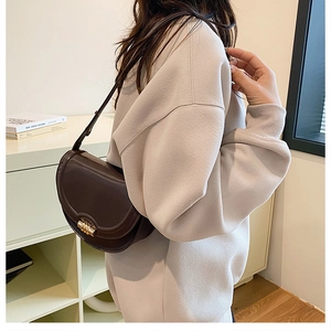 Dettaglio della borsa a sella marrone scuro con elegante chiusura a girello oro