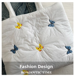 Detail of white quilted tote bag featuring vibrant blue and yellow butterfly embroidery