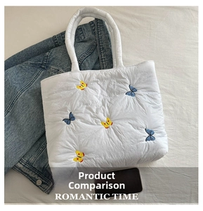 Detail of white quilted tote bag featuring vibrant butterfly embroidery and soft texture