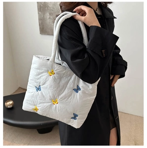 Close-up of white quilted tote bag featuring detailed butterfly embroidery on nylon