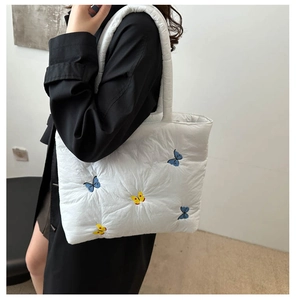 Detail of white quilted tote bag featuring delicate blue and yellow butterfly embroidery