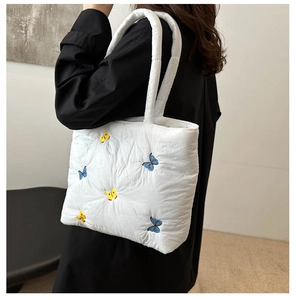 Close-up of white quilted tote bag featuring vibrant blue and yellow butterfly embroidery