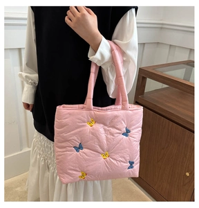 Detailed close-up of pink quilted tote bag with colorful butterfly embroidery textures