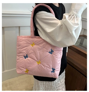 Detail of pink quilted tote bag featuring delicate blue and yellow embroidered butterflies