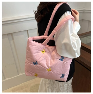 Detail of pink quilted tote bag featuring delicate blue and yellow butterfly embroidery