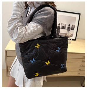 Detailed embroidery of colorful butterflies on a black quilted nylon tote shoulder bag