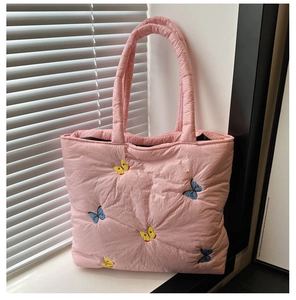 Close-up of pink quilted tote bag with blue and yellow butterfly embroidery details