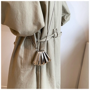Detail of silver shell-shaped mini bag with snake chain on khaki trench coat
