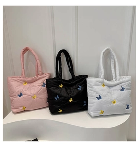 Detailed embroidery of yellow and blue butterflies on quilted tote bags in three colors