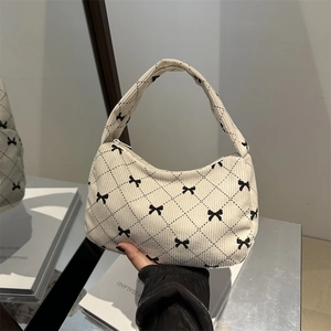 Quilted corduroy underarm bag in cream white with black bow pattern and zipper closure