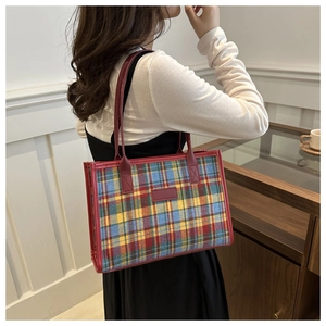 Detailed view of large plaid tote bag with colorful pattern and deep red leather straps
