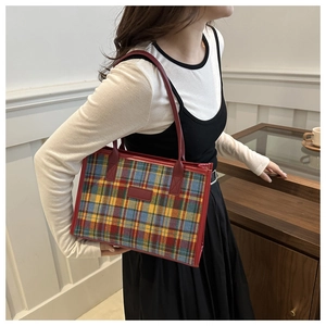 Dettaglio della borsa tote in tela con motivo scozzese colorato e manici in pelle rossa